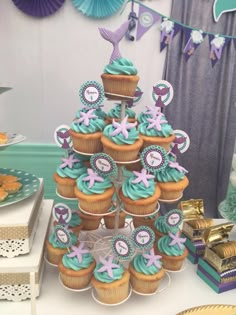 a table topped with cupcakes covered in blue frosting and under - the - sea decorations