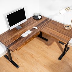 a wooden desk with a computer monitor and keyboard on it, in front of a white wall