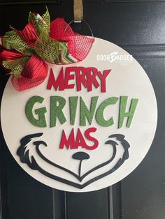 a merry grinchmas sign hanging on the front door with red and green bows