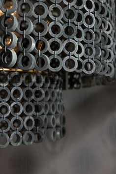 a bunch of metal circles hanging from a ceiling fixture with lights on each side and circular holes in the middle