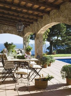 an outdoor patio with tables and chairs next to a swimming pool in front of the ocean