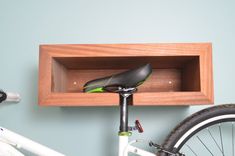 a bicycle is parked in front of a wooden shelf with a bike seat on it