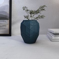 a blue vase sitting on top of a white table next to a framed photograph and books