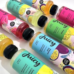 six different flavors of juice are lined up on a white surface, with the words juicy written in cursive writing