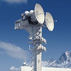 an antenna on top of a building with mountains in the background