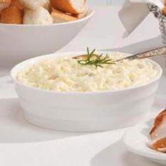 there is a bowl of food on the table with bread and other foods around it