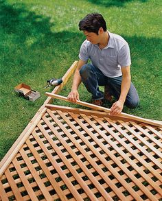 a man kneeling down on the ground working on a piece of wood that has been cut in half