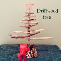 a christmas tree made out of driftwood sticks with a red candle and pine cones