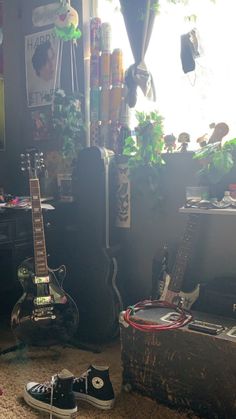 two guitars sitting on the floor in front of a window