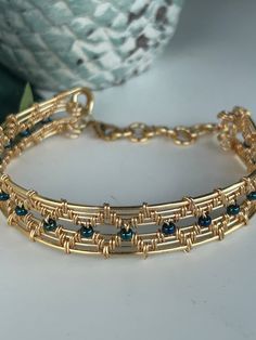 a close up of a bracelet on a table with a vase in the back ground