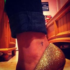 a woman's foot with a cross tattoo on it