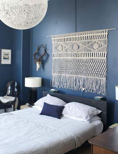 a bed sitting in a bedroom next to a wall hanging on the side of a blue wall