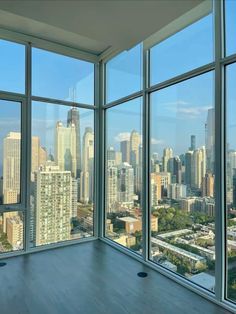 an empty room with large windows looking out on the cityscape and skyscrapers