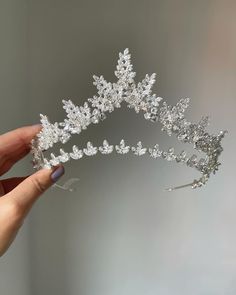 a hand holding a tiara in the shape of a snowflake with leaves on it