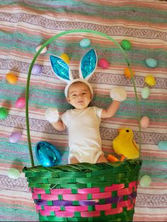 a baby laying in a basket with easter decorations