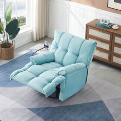 a blue recliner sitting on top of a rug next to a potted plant