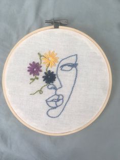 a close up of a embroidery on a white surface with a blue face and flowers