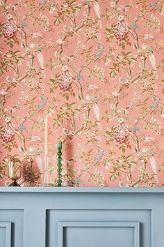 a pink wallpaper with birds and flowers on it in front of a blue door