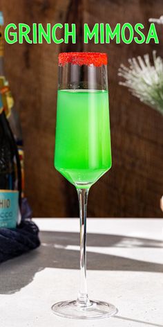 a green liquid in a wine glass with the words grinin'mimosa on it