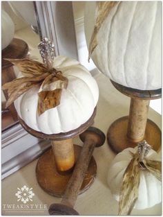 two white pumpkins sitting on top of wooden stand next to each other in front of a mirror