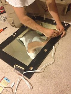 a man is working on an electronic device with wires attached to the back of it