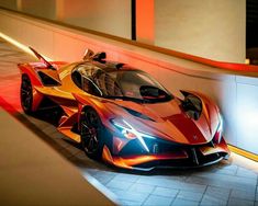 an orange and red sports car parked in a parking garage next to a wall with lights on it