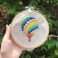 a colorful hot air balloon in the middle of a hand embroidered hoop hanging from a tree