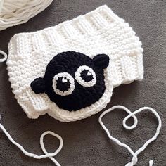 a crocheted black and white hat with two eyes on it, next to some yarn