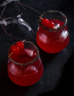 two glasses filled with red liquid and topped with cherries