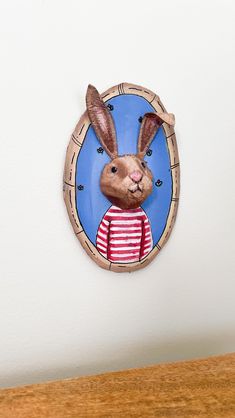 a paper cutout of a rabbit wearing a red and white striped shirt is mounted on the wall