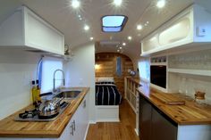 a galley kitchen with wood counter tops and stainless steel appliances