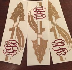 three white and gold decals sitting on top of a wooden table