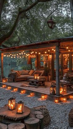 a small cabin with lots of lights on the porch and patio, surrounded by trees