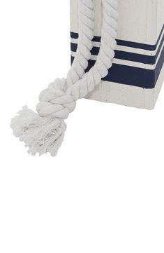 a white and blue striped bag with tassels hanging from it's side