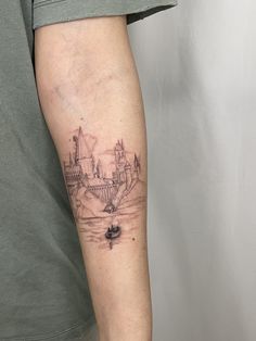 a man's arm with a castle tattoo on the left side of his arm