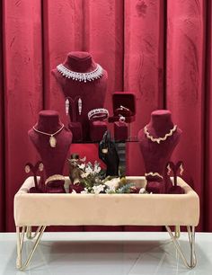 a table topped with lots of red and white jewelry pieces next to a red curtain