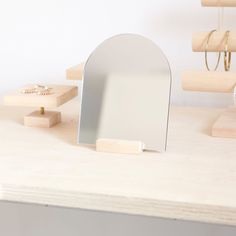 a mirror sitting on top of a wooden table next to rings and necklaces in front of it