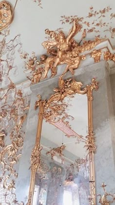 an ornate gold mirror hanging from the ceiling in a room with white walls and ceilings