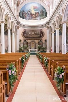 the interior of a church with pews and flowers on the aisle, decorated with floral arrangements