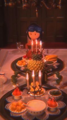 a table topped with plates and candles next to a doll sitting on top of a pineapple