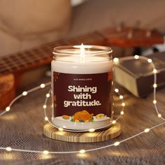 a lit candle sitting on top of a wooden table next to a string of lights