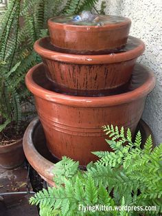 three clay pots are stacked on top of each other with water coming out of them