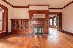 an empty living room with wood paneling and fireplace