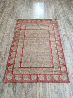 a red and beige area rug on the floor in a room with hard wood floors