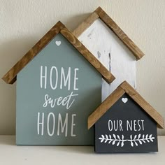 two small wooden houses sitting next to each other on a table with the words home sweet home painted on them