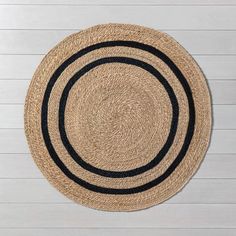 a black and tan rug on top of a white wooden floor next to a wall