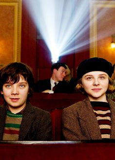 two people are sitting in the middle of a movie theater and one is staring at the camera