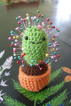 a crocheted cactus sitting on top of a pot filled with pins and needles