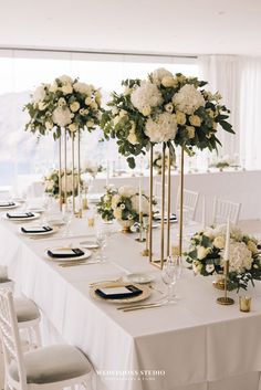 a long table with white flowers and gold place settings