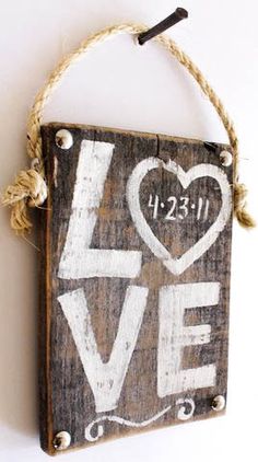 a wooden sign with the word love painted on it and rope hanging from a hook